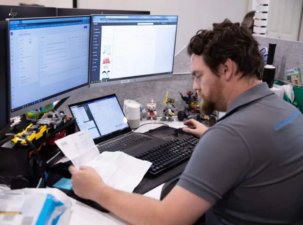 A member of the Envisage Technology Team at his desk looking at paperwork
