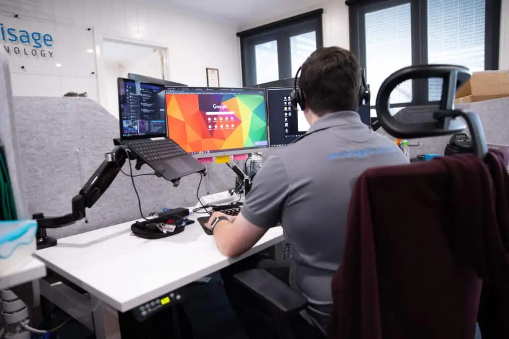 Envisage Technology team member at his desk working across multiple monitors