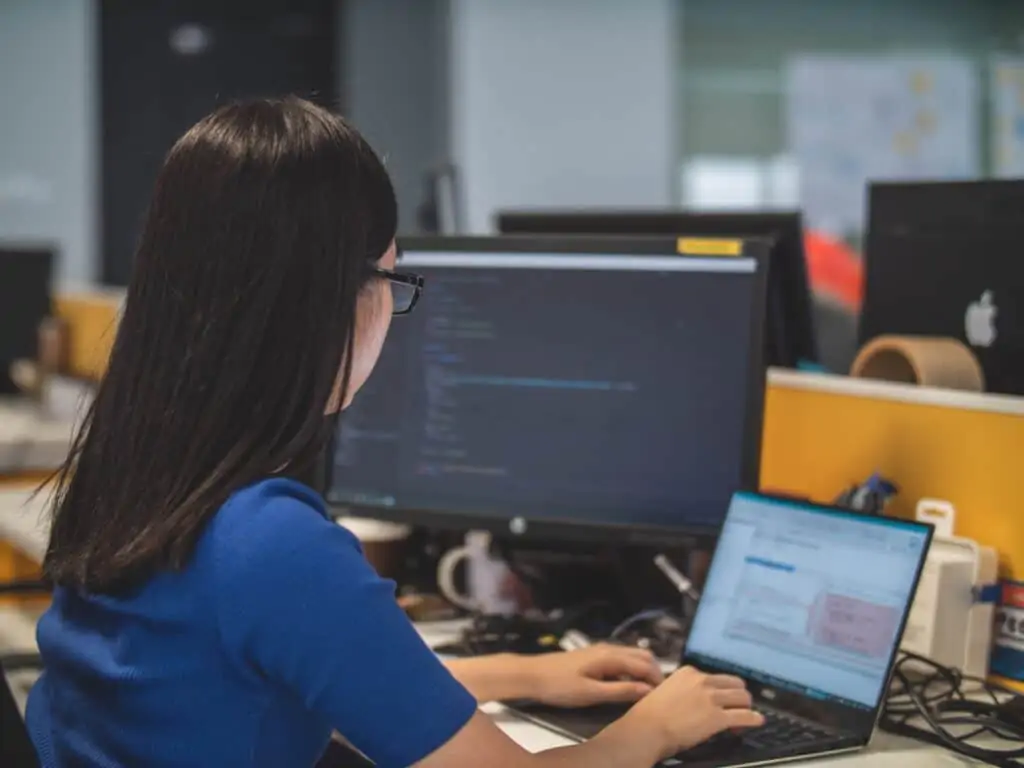 A member of the Envisage Technology team working at her laptop setting up and Information technology password manager for a client