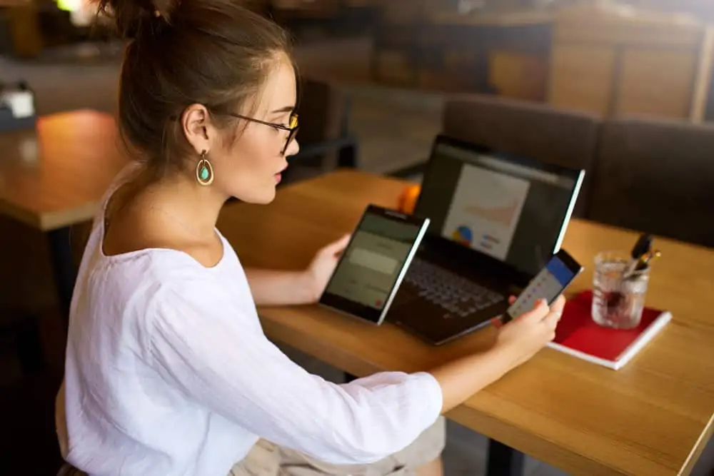 Woman in white shirt using tablet, laptop and mobile devices