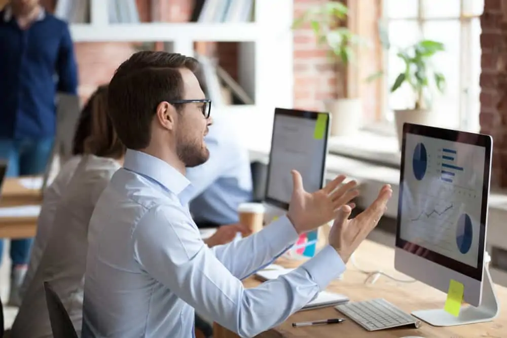 A male employee is looking at data on a computer screen