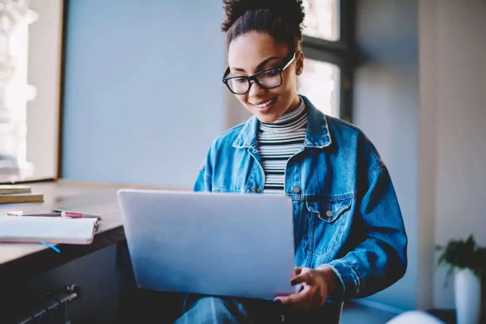 Woman in denim jacket smiling down at computer screen