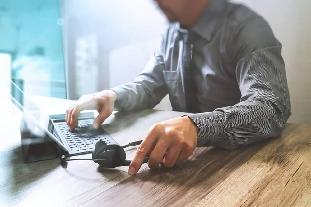 Man using Voip headset whilst working at his computer