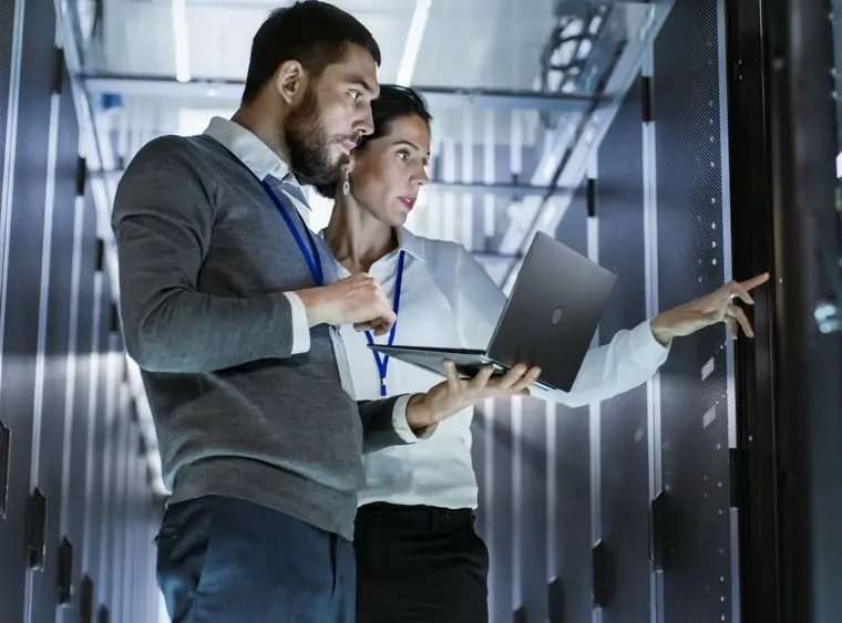 It specialists discuss work, standing in a data centre, the rack server cabinet is open